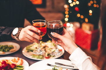 Man and woman drink red and white wine.  Сlose-up of hands with glasses. They celebrate the new year.