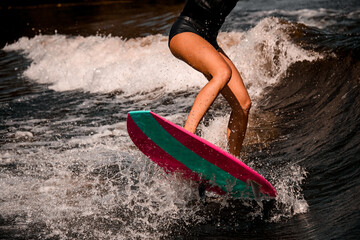close-up of beautiful tanned legs of woman jumping on wave on surf style wakeboard