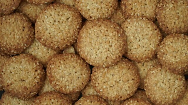 Top view of fresh baked sweet cookies with sesame rotate on tray. Close up of food dessert background. Bakery and pastry shop concept