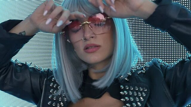 beautiful young woman posing against a led panel. teenager with alternative look posing with a colored wig