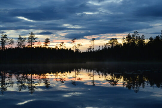 Sunset Late Summer Evening. Rovaniemi Finland. Strong Blue Cloudy Sky. Almost Dark, Colorful Skyline, Wavy Water, Reflection From Water.