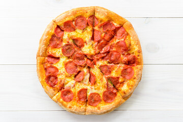 Peperoni pizza on a light wooden table. Horizontal orientation top view, flat lay.