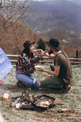 stylish young couple of travelers. Family on a walk in the mountains laid out a tent, prepare breakfast and plan a further itinerary