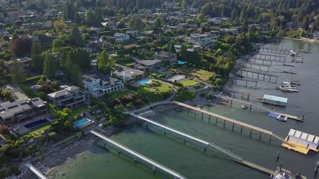 Ocean front mansions of rich people in drone aerial view. Beautiful homes with dock, pier along the sea. Private boats and pools on a little hill in Vancouver Pacific Coast Indian Arm. Dream houses