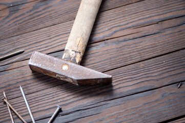 Old vintage hammer and nails on a wooden background, close-up, selective focus.
