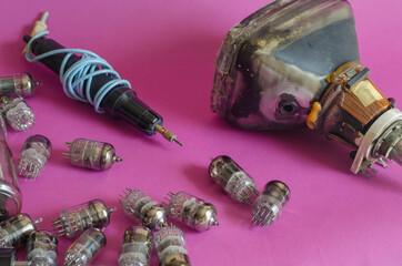 A group of random radio tubes, an induction soldering iron and an old picture tube on a pink...
