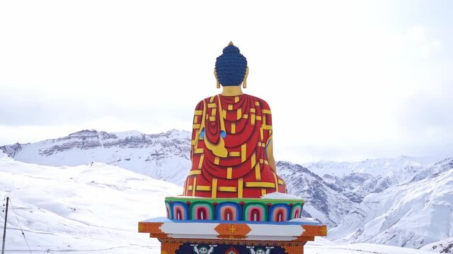 Back View Of Langza Buddha Statue With A Snowy Mountain In The Background During Winter Near The Spiti Valley In Langza, Himachal Pradesh, India. - zoom out shot