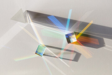 Glass geometric figures prisms with light diffraction of spectrum colors and complex reflection with trendy light and hard shadows on a white background