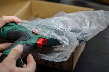 Male hands unpack and examine the electric drill.