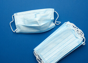 blue disposable medical mask on a blue background, personal protective equipment for the...