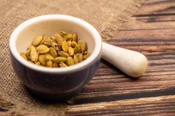 Cardamom in a ceramic mortar and pestle, close-up, selective focus.