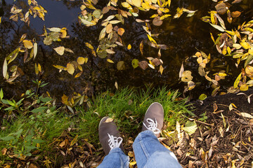 Legs in sport shoes on yellow autumn leaves in grass. Footwear, fall and season concept