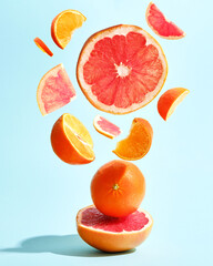 Concept levitation of juicy grapefruits and oranges on a bright blue paper background