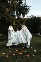 Friends with ghost costume playing and spinning at the park
