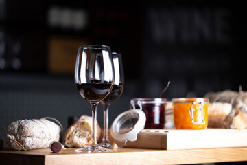 Wine glasses on table with bread and jam, dark background. Shallow depth of field, selective focus