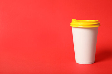 Takeaway paper coffee cup on red background. Space for text