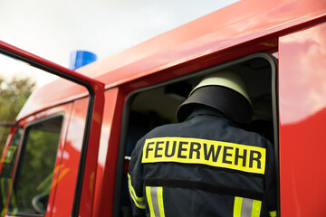 Symbolbild Feuerwehr mit Feuerwehrmann vor einem Feuerwehrauto