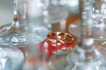 Wedding rings lying between crystal glasses