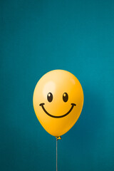 Stock photo of a yellow balloon with smiley face on a blue background