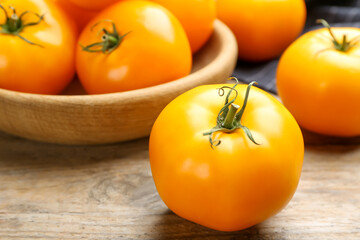 Ripe yellow tomato on wooden table, closeup