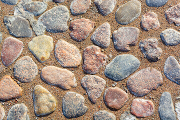 Flat sea cobblestones on a sandy beach. Rounded stones with different form background cut out. Large rocks mosaic wallpaper with different size and color texture. Mineral material edge curves top view