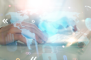 Double exposure of world map hologram with man working on computer on background. Concept of worldwideweb.