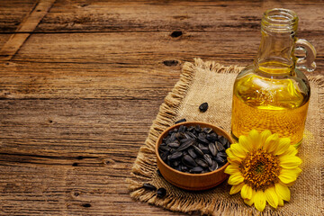 Sunflower oil in glass cruet with flower head and seeds in wooden bowl