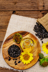 Sunflower oil in glass cruet with flower head and seeds in wooden bowl