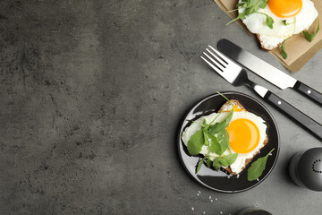 Delicious sandwich with arugula and fried egg on grey table, flat lay. Space for text