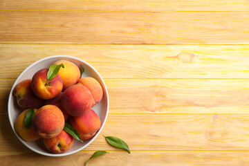 Fresh sweet peaches in bowl on wooden table. Space for text