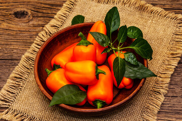 Ripe whole orange mini peppers in clay bowl