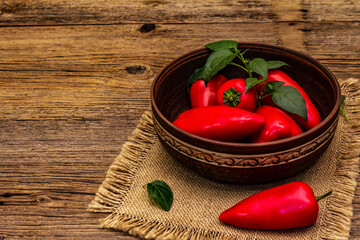 Ripe whole red mini peppers in clay bowl