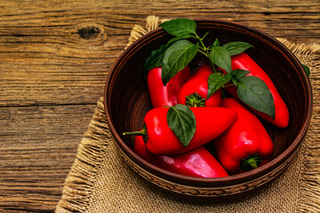 Ripe whole red mini peppers in clay bowl