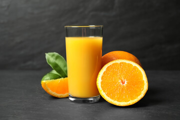 Fototapeta na wymiar Glass of orange juice and fresh fruits on grey table