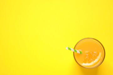 Glass of orange juice on yellow background, top view. Space for text