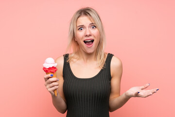 Young blonde woman with a cornet ice cream over isolated pink background with shocked facial expression