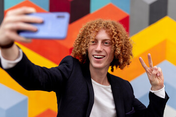 Male hipster taking selfie against colorful wall