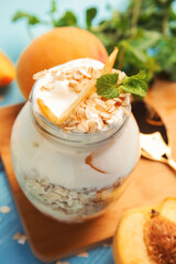 Tasty peach dessert with yogurt and granola on light blue wooden table, closeup
