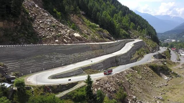 Dump Truck Driving Uphill And Turning On The Sharp Curve Road By The Himalayan Mountains Near The Manali Town In Himachal Pradesh, India. - aerial drone shot