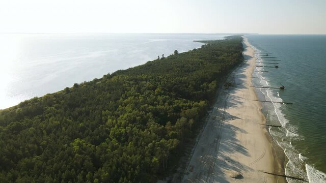 Aerial side movement over the forest, white sand beach, and baltic sea in Kuznica, Pomeranian Voivodeship (north Poland), a district of the seaside town of Jastarnia