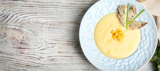 Delicious corn cream soup served on white wooden table, flat lay with space for text. Banner design
