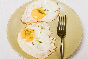 Close-up two fried eggs on plate with dill