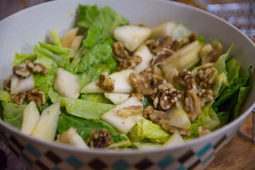 Lettuce salad with Persian walnuts, and slices of apples, served in a bowl 