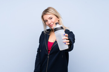 Obraz premium Young sport blonde woman over isolated blue background with sports water bottle