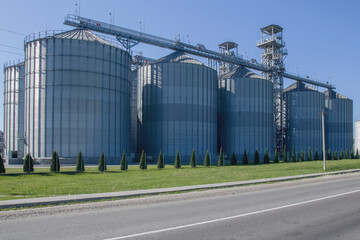 Fototapeta na wymiar Granary. A large modern agro-processing plant for the storage and processing of grain crops. Large metal barrels of grain. Granary elevator. Horizontal image.
