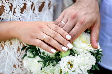 Obraz na płótnie Canvas Newly wed couple's hands with wedding rings.