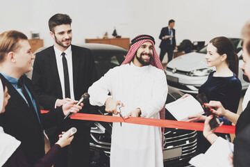 An Arab man stands with scissors in his hands. 