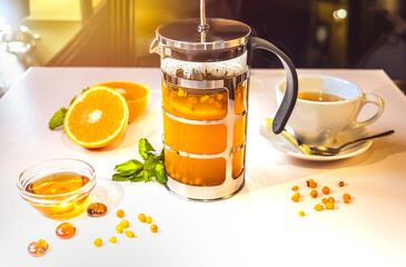 Tea in a teapot with physalis and honey on a white table against the background of the restaurant