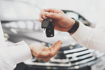 Salesman is giving keys for new car to man.