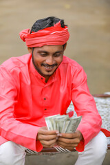 Young indian farmer counting money